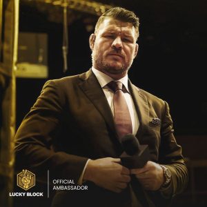 An image of former UFC fighter Michael Bisping buttoning up a suit jacket and holding a microphone